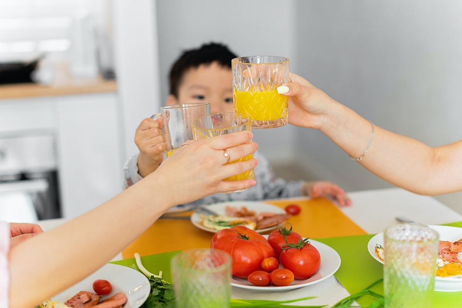 How Standard Process Congaplex Helps when you are Sick a Family with a Young Child at a Table Raising a Glass of Orange Juice to Toast