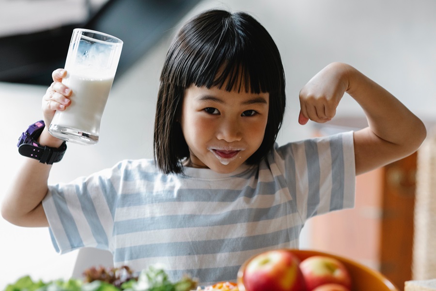 How Standard Process Congaplex Helps when you are Sick a Young Girl Flexing Her Arms with a Glass of Milk in One Hand