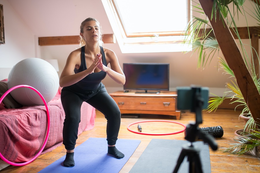 Weekly Jillian Michaels Workout Routines a Woman Doing a Workout in Her Bedroom with a Phone on a Tripod in Front of Her