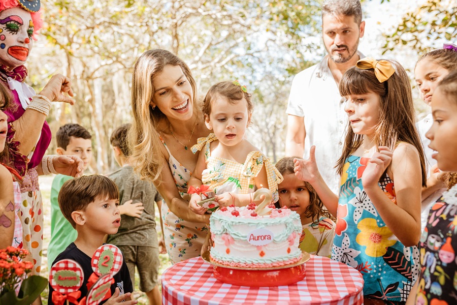 How to Set a Table for your Child's Birthday Party People Celebrating a Birthday Party in a Park Standing Around a Picnic Table with a Cake on Top