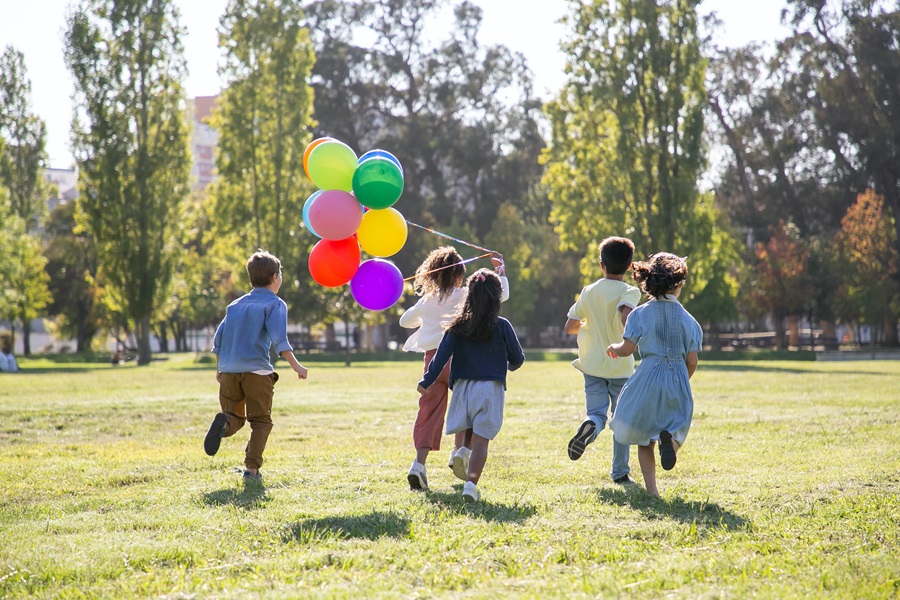How to Set a Table for your Child's Birthday Party a Group of Kids Playing in a Park Running Around Holding Birthday Balloons