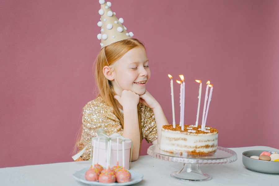 How to Set a Table for your Child's Birthday Party Close Up of a Little Girl Looking at a Naked Birthday Cake with Lit Candles 