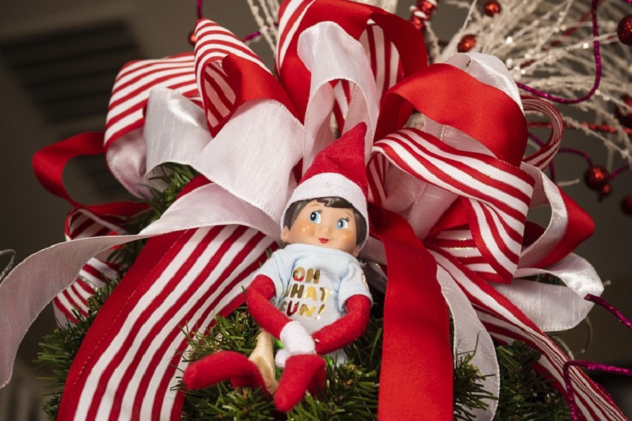 Introduce Elf on the Shelf an Elf Laying on  Christmas Ribbon