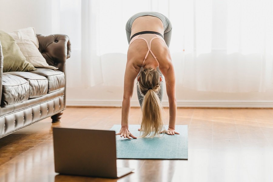 Ways to Modify Focus T25 Workouts Woman Doing Yoga in Her Living Room Next to a Laptop