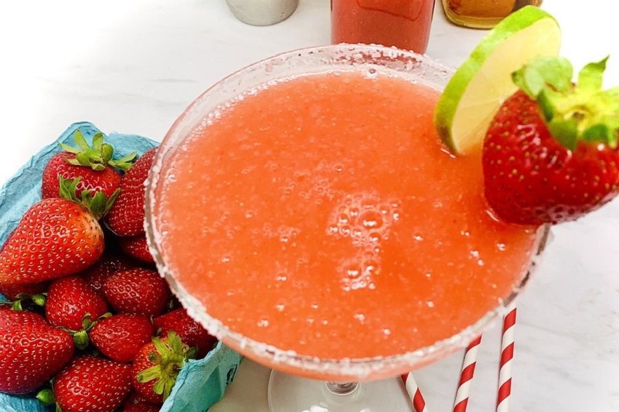 4th of July Recipes Close Up of a Strawberry Margarita Next to a Container of Strawberries