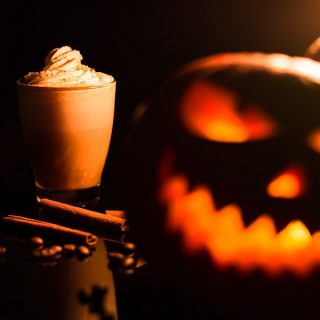 Pumpkin Drinks on a Blaco Surface with a Jack O Lantern in the Forefront