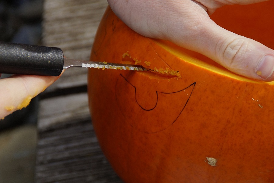 Free DIY Pumpkin Stencils Close Up of Someone Carving a Pumpkin