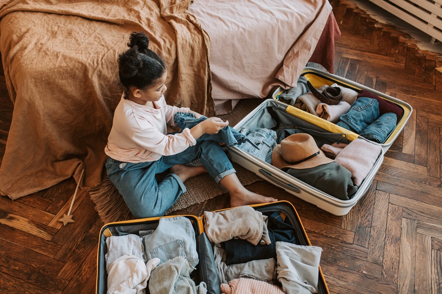 Printable Vacation Rental Packing List a Young Girl Packing Two Suitcases on the Floor of Her Room