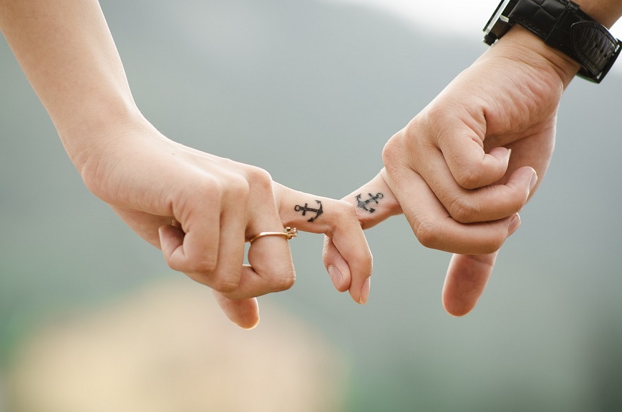 Stillbirth Quotes to Help you Cope Close Up of a Couple's Hands with Their Index Fingers Hooked Together and Small Anchor Tattoos on Each Index Finger