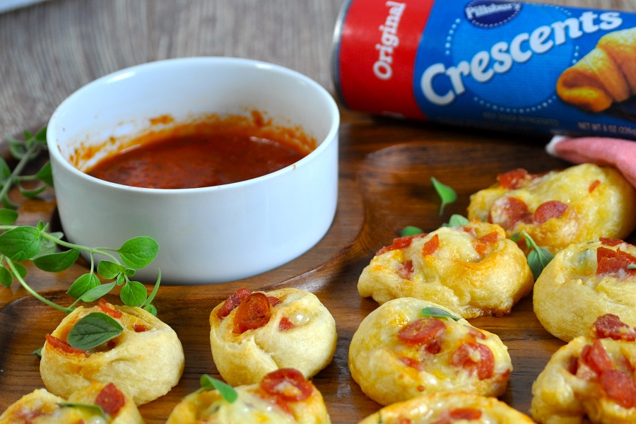 Bite Sized Snacks to Nibble On Close Up of Pepperoni Pinwheels with a Small Dish of Marinara Sauce and a Pillsbury Crescent Rolls Tube in the Background
