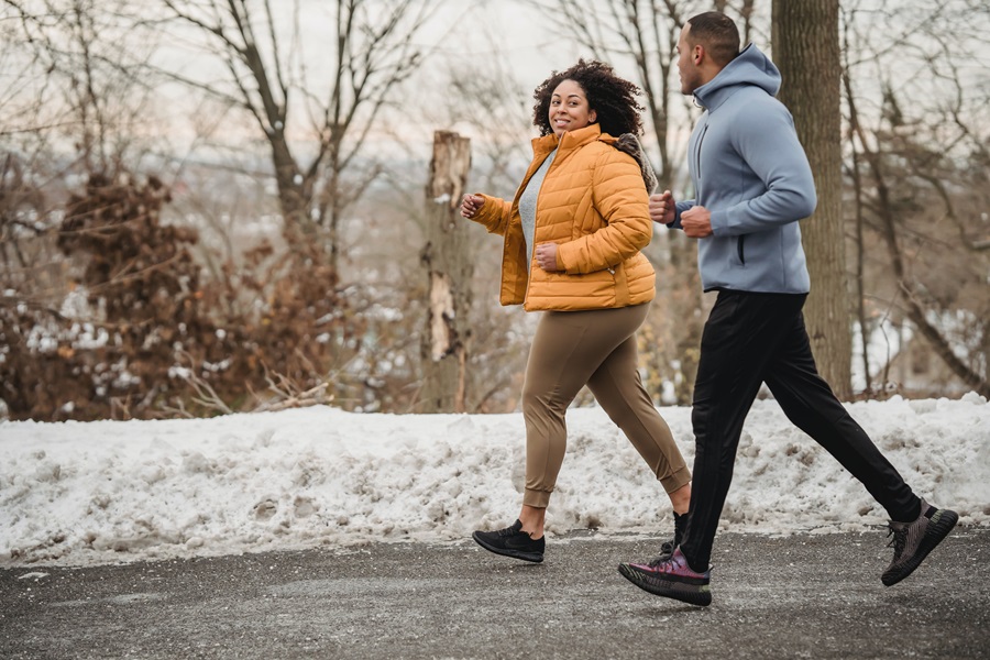 BODYSHRED Escalate Printable Workout Checklist a Man and a Woman Wearing Workout Clothing for Cold Weather While Jogging Outside with Snow on the Ground