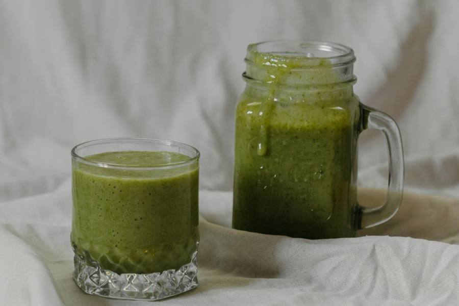Jillian Michaels Breakfast Ideas Close Up of a Glass of Green Juice Next to a Small Mason Jar of Green Juice