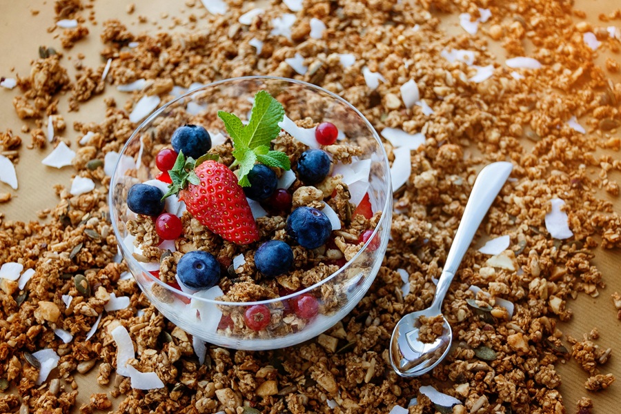 Jillian Michaels Breakfast Ideas a Glass Bowl of Yogurt, Oats, and Fruit on a Surface Covered in Oats