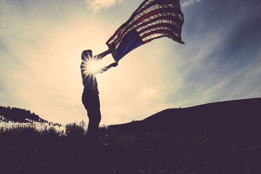 DIY Patriotic Decorations Silhouette of a Man Flapping an American Flag in the Wind with the Sun Behind Him 
