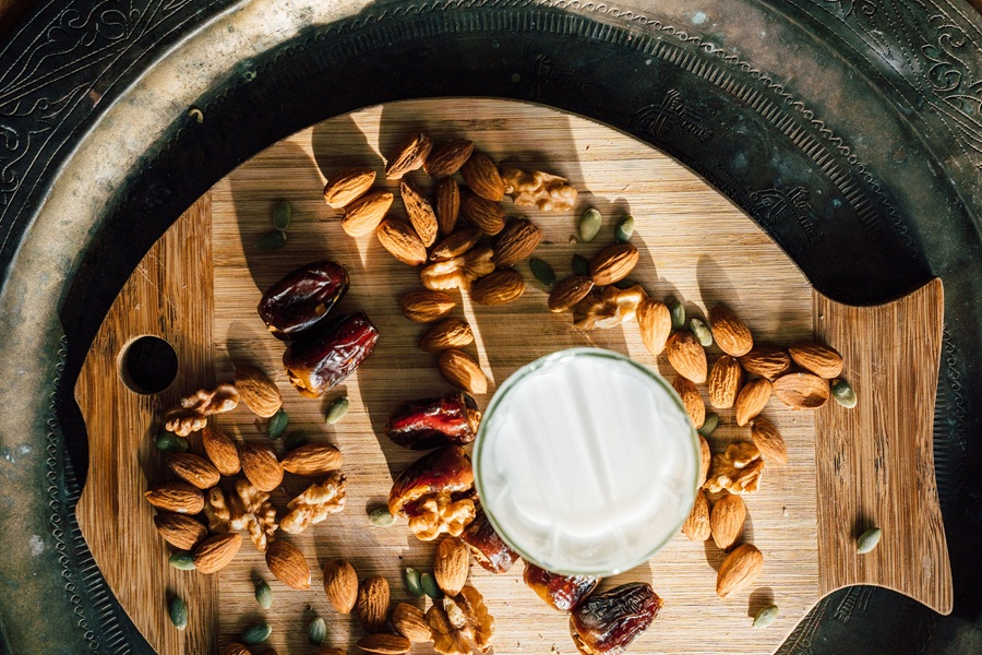 How to Go Dairy Free a Glass of Milk Alternative Surrounded by Different Types of Nuts