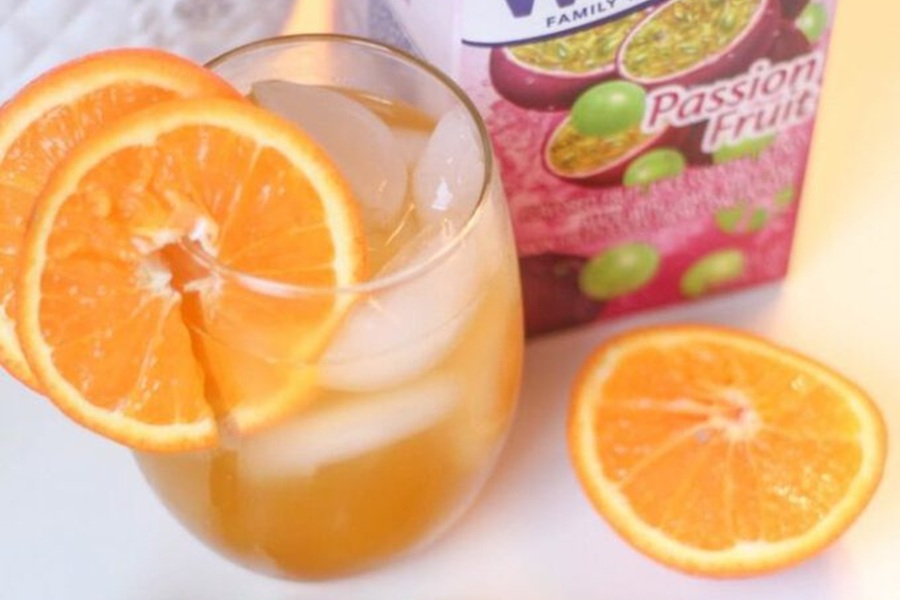 Easy Fireball Cocktail Recipe in a Glass Sitting Next to Fruit Juice
