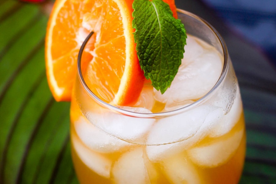 Easy Fireball Cocktail Recipe Close Up of a Cocktail Garnished with Orange Slices and Mint Leaves