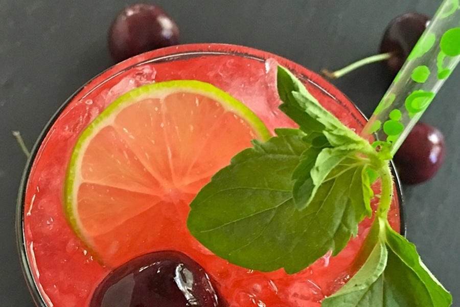 Homemade Blackberry Mojito Recipe Close Up of the Top of a Blackberry Mojito Garnished with a Lime Slice, Cherry, and Mint Sprig