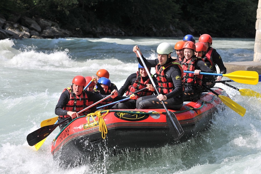 Whitewater Rafting Terms and Lingo To Know a Group of People in a Red and Black Raft Going Down a River