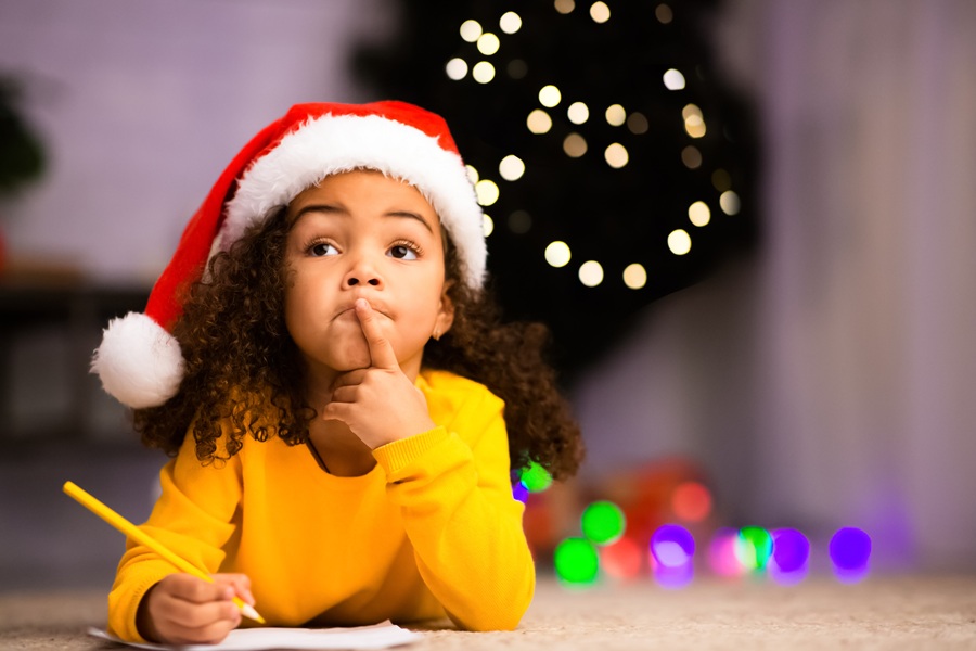 DIY Elf on the Shelf Clothes a Little Girl Wearing a Santa Hat Laying on the Ground, Making a List for Christmas