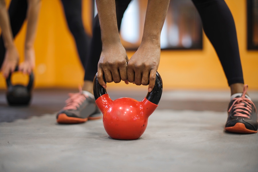 Core De Force Review Close Up of a Person's Hands Holding a Kettlebell on the Ground