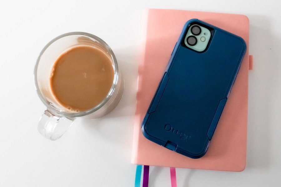 Otterbox Levels of Protection Overhead View of a Phone in a Commuter Case Lying on a Notebook Next to a Cup of Coffee