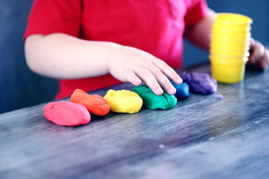 Activities for Kids Before Electronics Play Dough in Different Colors with a Young Child's Hand on One Pile