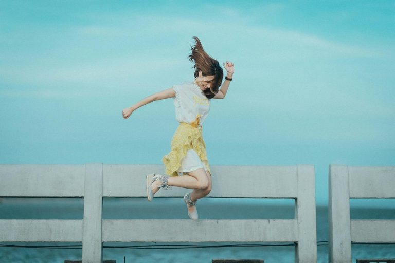 Standard Process Ovex a Woman Jumping in the Air Celebrating with a Body of Water in the Background