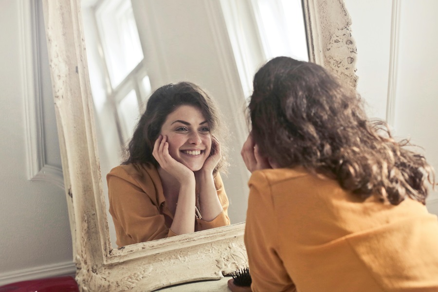 Standard Process Ovex a Woman Looking at Herself in the Mirror Smiling