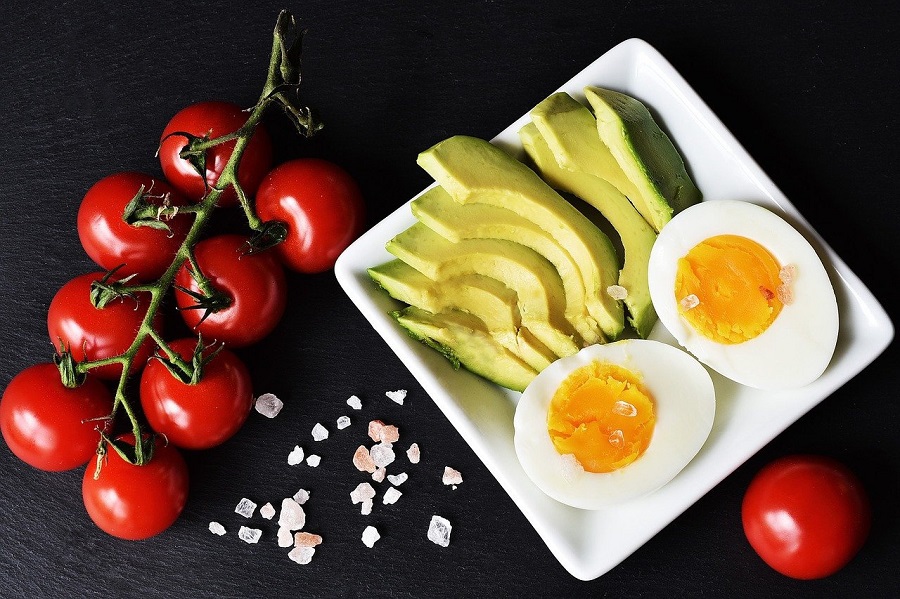 Ketogenic Diet Plan Shopping Lists Overhead View of a Plate with Hard Boiled Egg Halves, Sliced Avocado, and Tomatoes