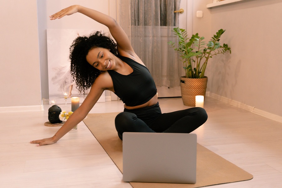 Shaun Week Quotes for Workout Motivation a Woman Stretching Before a Workout on a Yoga Mat While Looking at a Computer