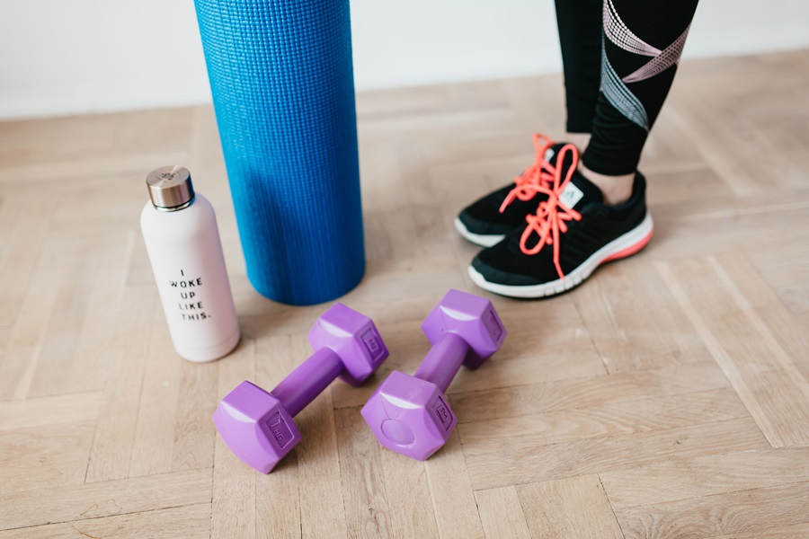 21 Day Fix Printable Workout Calendar Close Up of Dumbbells, a Yoga Mat, and a Water Bottle Sitting on the Ground with a Woman Standing Next to Them