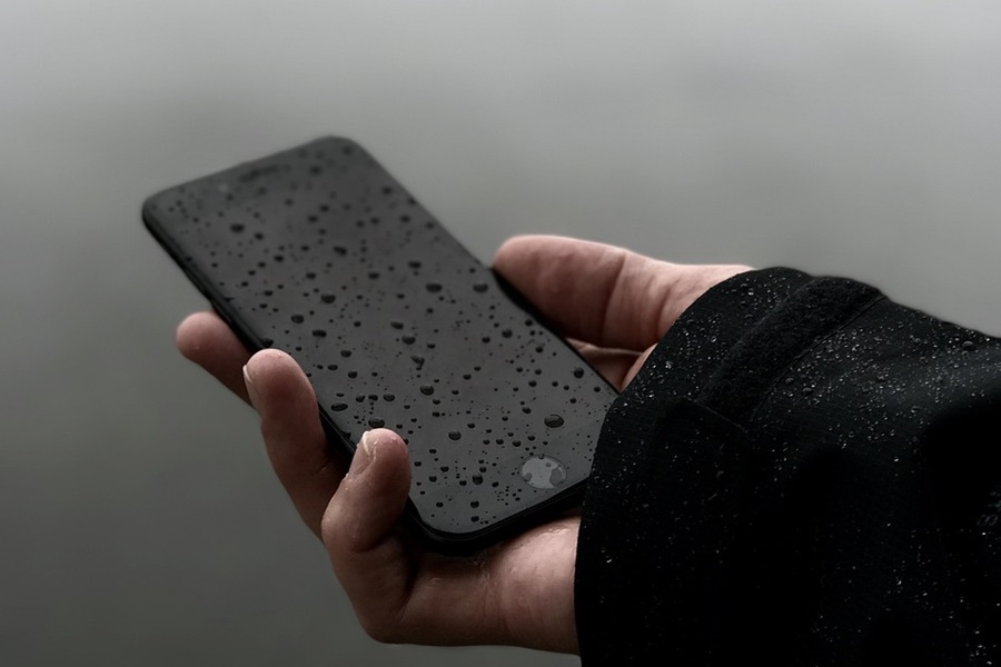 Which Otterbox Case is Waterproof a Person Holding Out a Phone in the Rain with Water Droplets on the Screen