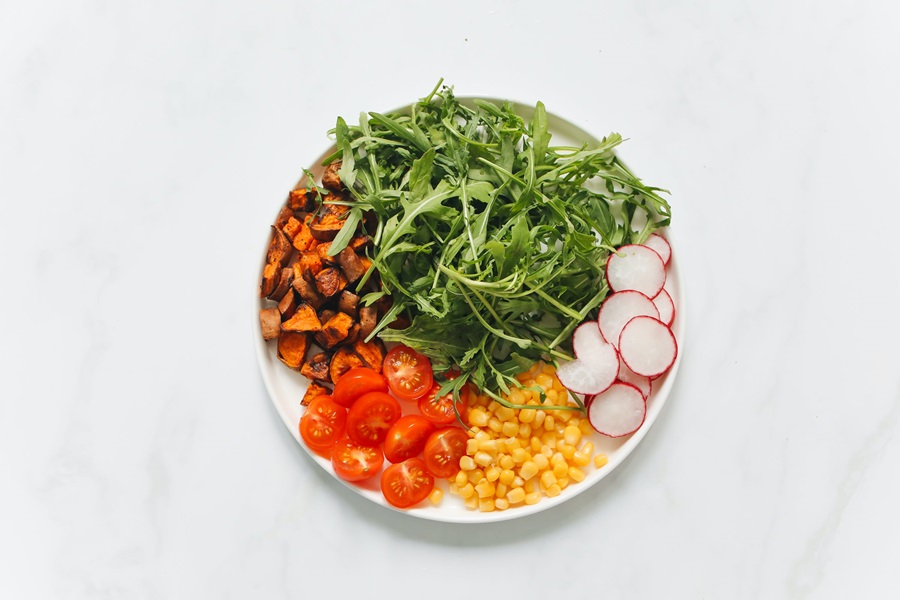 80 Day Obsession Timed Nutrition Tips a Plate of Salad with Arugula, Corn, Radishes, and Carrots