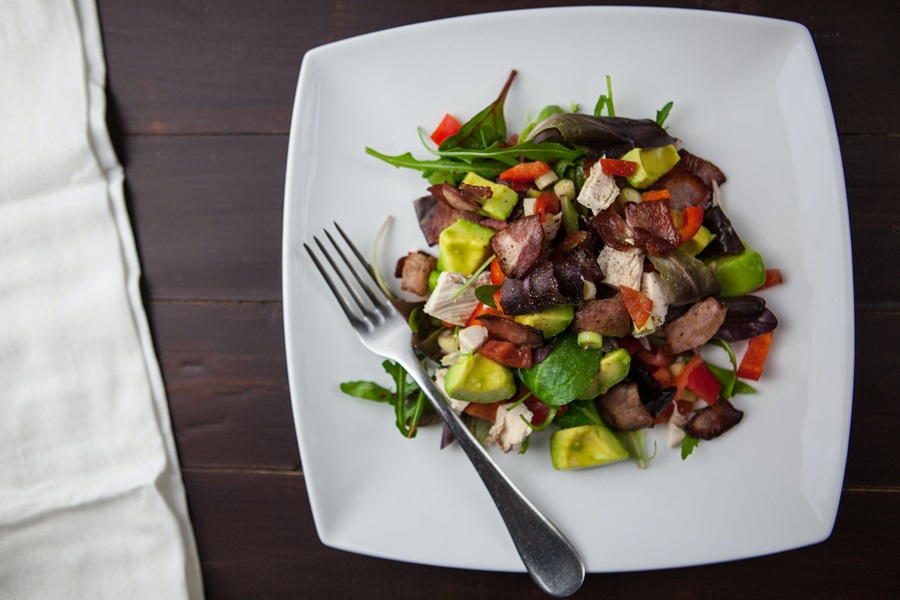 80 Day Obsession Timed Nutrition Tips a Salad Topped with Beef Tips on a White Plate with a Fork