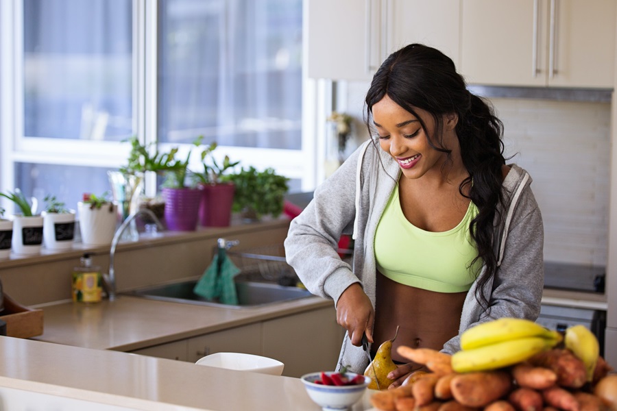 80 Day Obsession Timed Nutrition Tips a Woman Preparing Healthy Food in Her Kitchen While Wearing Workout Clothes