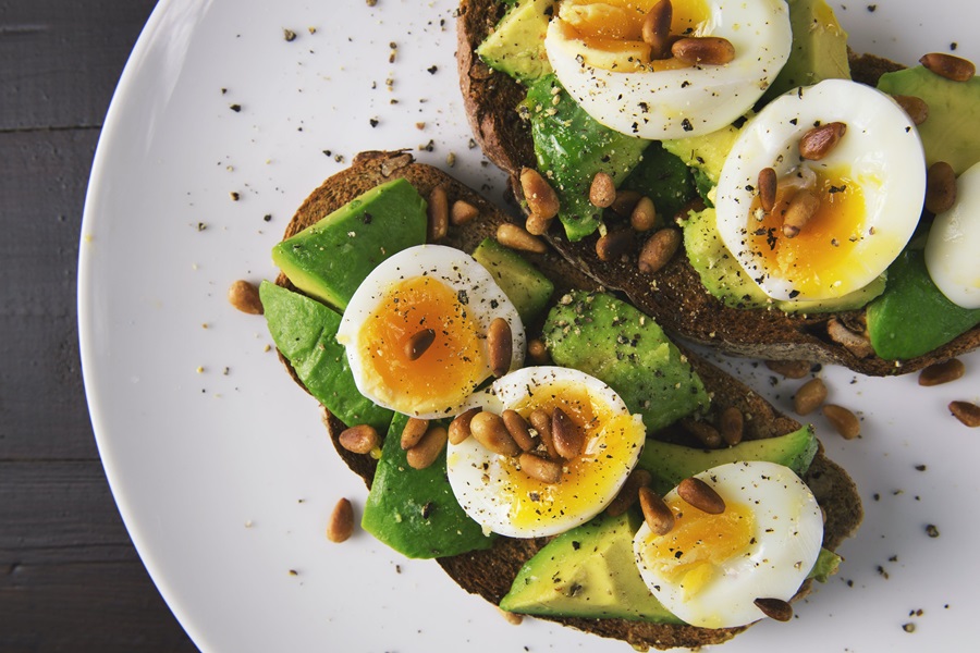 80 Day Obsession Timed Nutrition Tips Two Slices of Avocado Toast Topped with Hard Boiled Eggs