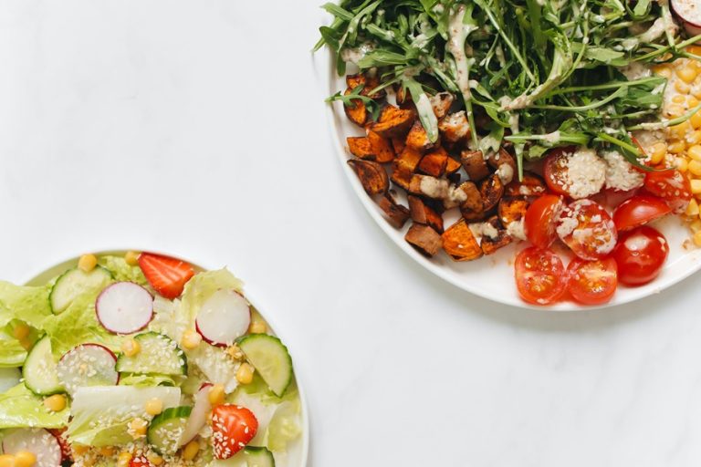 80 Day Obsession Timed Nutrition Tips Two Plates of Different Salads, One Basic and the Other with Spring Mix