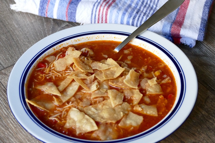 Easy Crock Pot Chicken Tortilla Soup Recipe Close Up of a Bowl of Chicken Tortilla Soup with a Spoon and a Towel Nearby