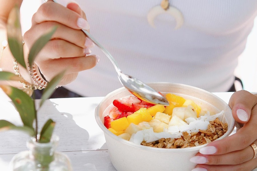 Standard Process A F Betafood Uses Close Up of a Yogurt Bowl Topped with Fruits and Oats on a Table with a Person Holding a Spoon Above it