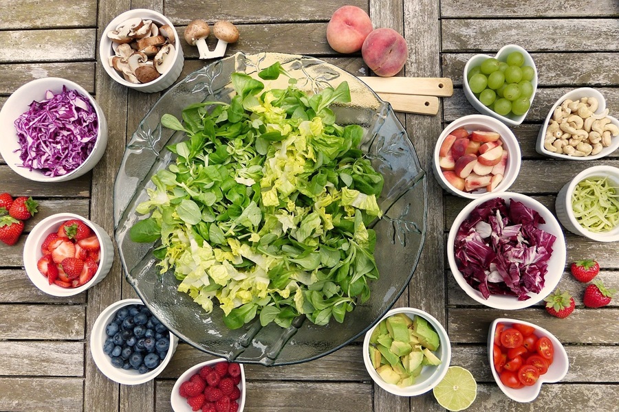 2B Mindset vs 21 Day Fix  Overhead View of a Salad Bowl Filled with Lettuce Surrounded By Smaller Bowls of Salad Toppings