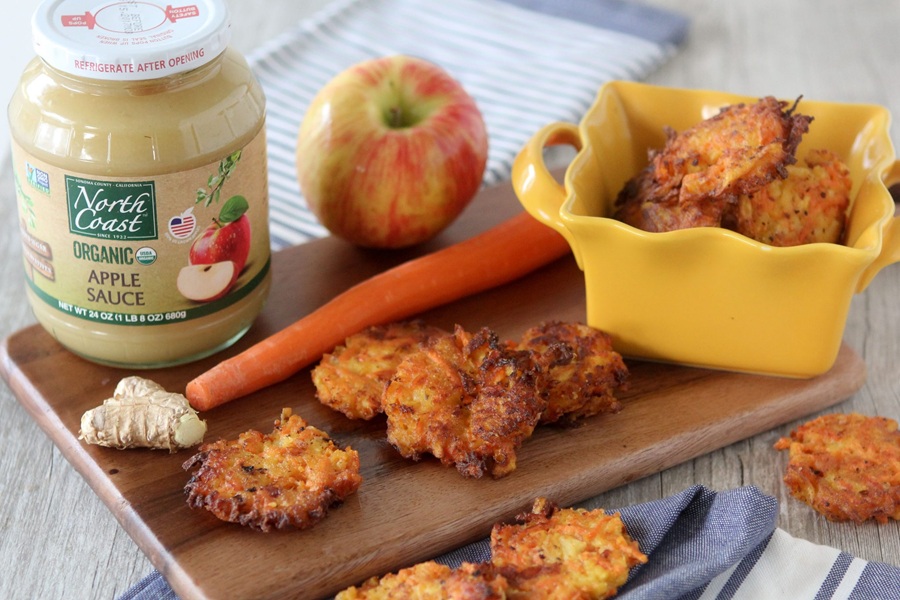 Carrot, Ginger + Apple Fritters on a Cutting Board with Raw Carrots, Apples, and a Jar of Apple Sauce 2B Mindset Snack Recipes