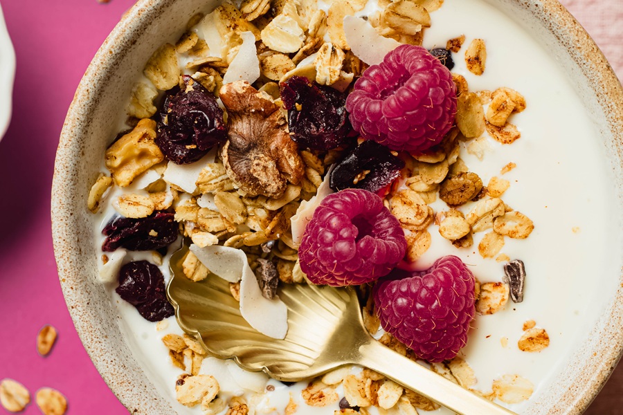 Easy Vegan Granola Recipe a Bowl of Granola and Milk with Fresh Raspberries and a Spoon