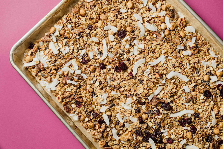 Easy Vegan Granola Recipe Granola on a Baking Sheet on a Pink Surface