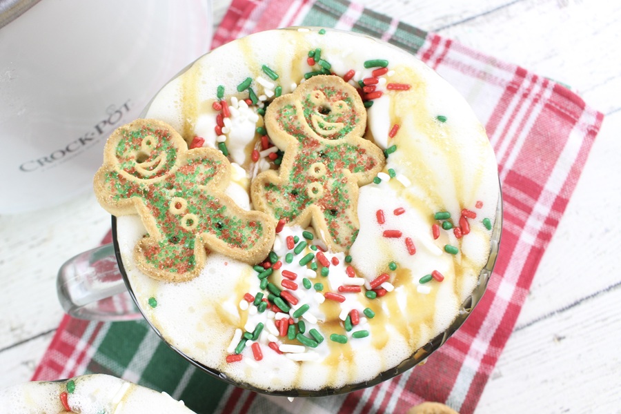 Gingerbread Latte Recipe Overhead View of a Latte Topped with Whipped Cream, Red, Green, and White Sprinkles, and Two Small Gingerbread Cookies