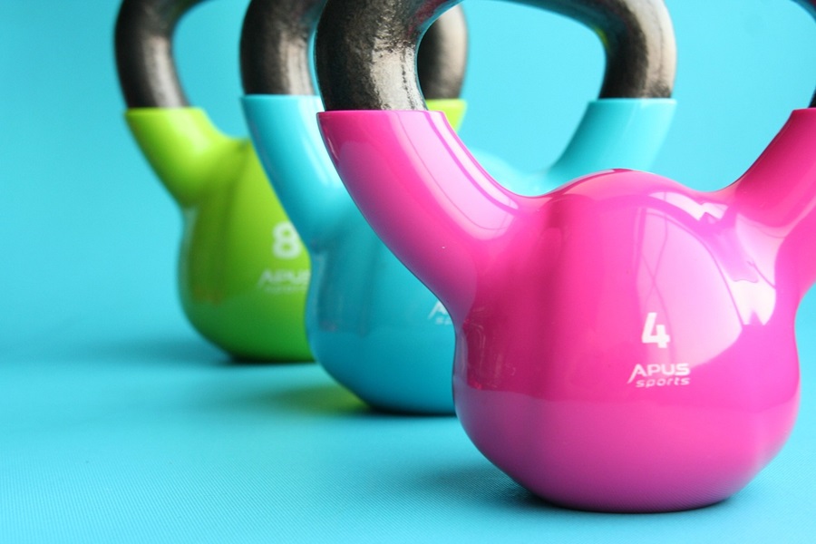 Kettlebell Exercises You Should Do Each Day a Row of Brightly Colored Kettlebells on a Bright Blue Surface