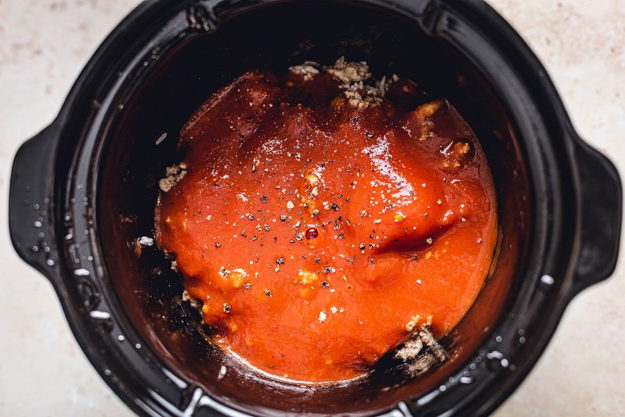 Crockpot Unstuffed Cabbage Rolls Recipe Overhead View of a Crockpot with Tomato Sauce Mixture Layered On Top of the Meat Mixture