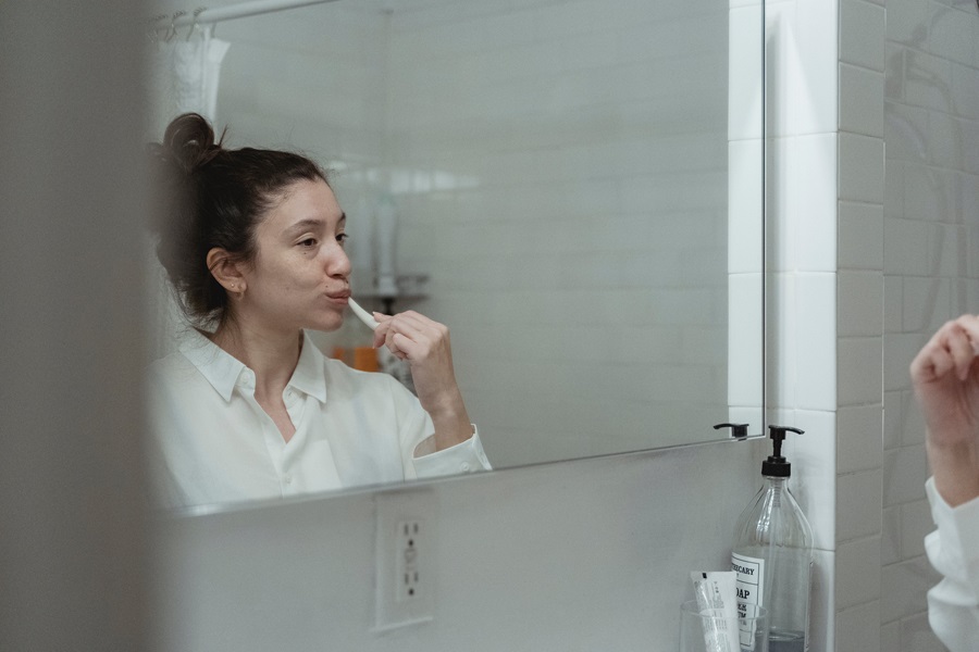 Exercises to Do While Brushing Your Teeth a Woman Brushing Her Teeth in a Mirror