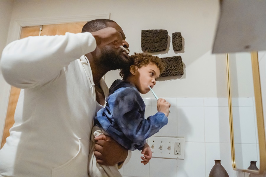 Exercises to Do While Brushing Your Teeth a Man Holding His Son While Both of Them Brush Their Teeth