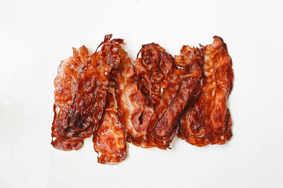 Keto Carb Limit vs Low Carb Limit a Row of Cooked Bacon on a White Surface